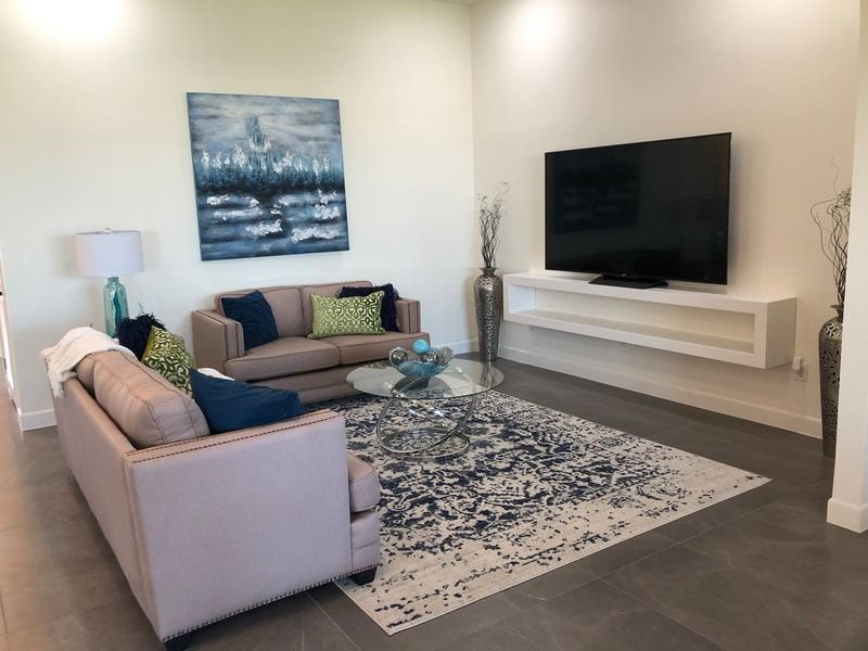 A living room with a couch , rug , television and painting on the wall.