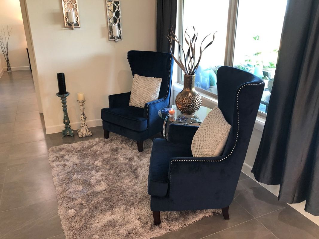 A living room with two blue chairs and a rug.
