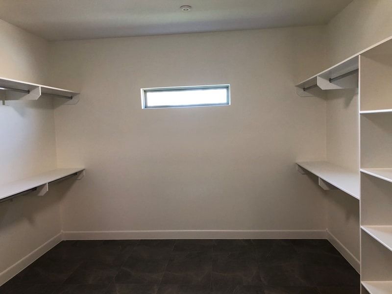 An empty walk in closet with shelves and a window.