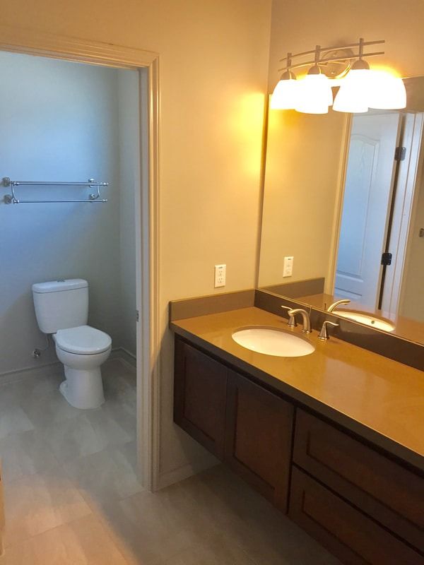 A bathroom with a toilet , sink and mirror.