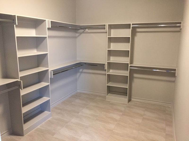 A walk in closet with lots of shelves and clothes racks.