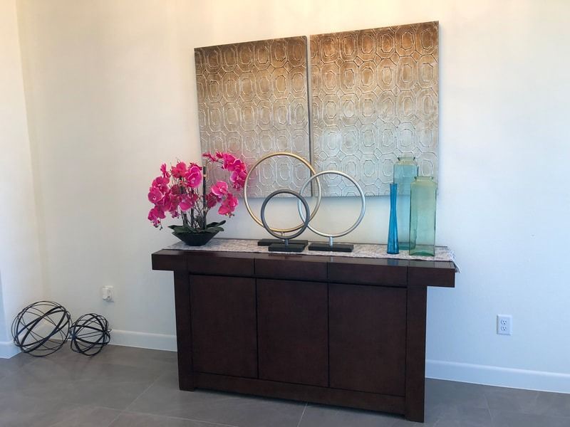 A table with a vase of flowers and a painting on it