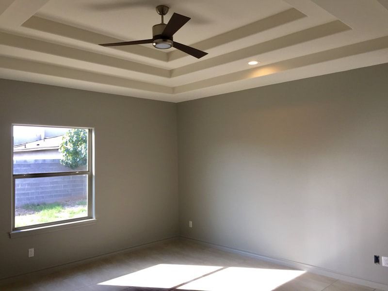 An empty room with a ceiling fan and a window