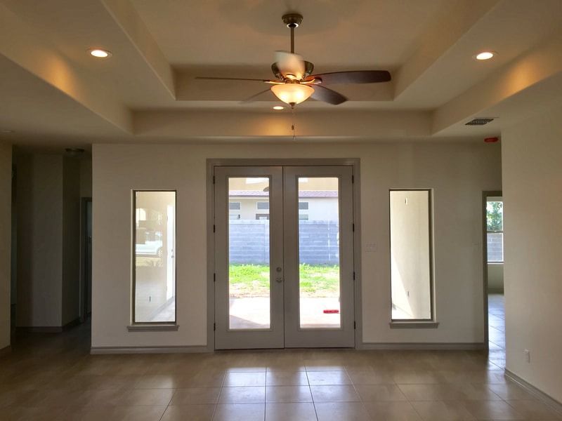 An empty room with a ceiling fan and sliding glass doors