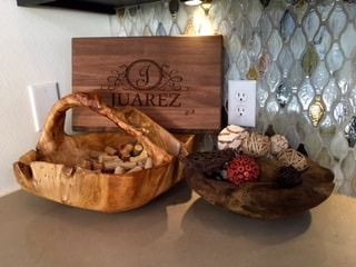 Two wooden bowls are sitting on a counter next to a wooden cutting board.