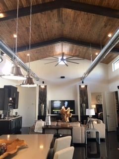 A living room with a wooden ceiling and a ceiling fan.