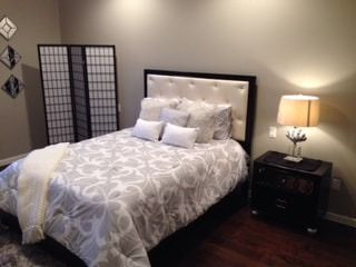 A bedroom with a bed , nightstand , lamp and screen.