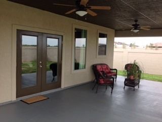 A porch with chairs and a ceiling fan