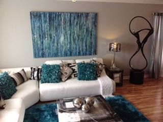 A living room with a white sectional couch and a blue rug.