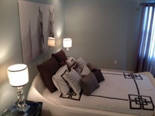 A bedroom with a bed and two lamps and a painting on the wall