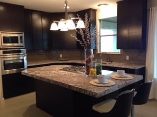 A kitchen with granite counter tops and black cabinets