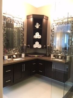 A bathroom with two sinks , two mirrors , and a walk in shower.