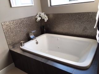 A white bathtub in a bathroom next to a window.