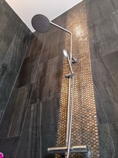 A close up of a shower head in a bathroom.