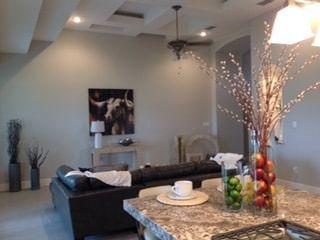 A living room with a black couch and a painting on the wall