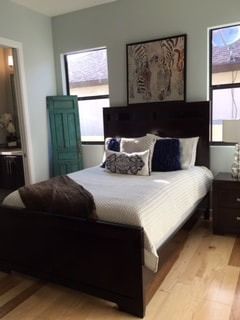 A bedroom with a bed , nightstand , and two windows.