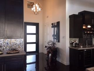 A kitchen with black cabinets and a chandelier hanging from the ceiling
