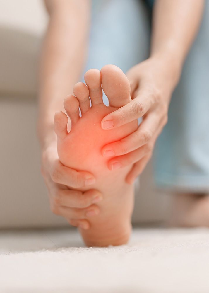 Person holding foot, showing red area indicating pain.