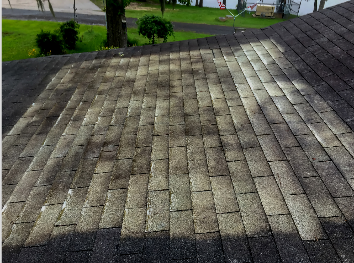 A weathered shingle roof with dark staining, likely from algae growth, outdoors.
