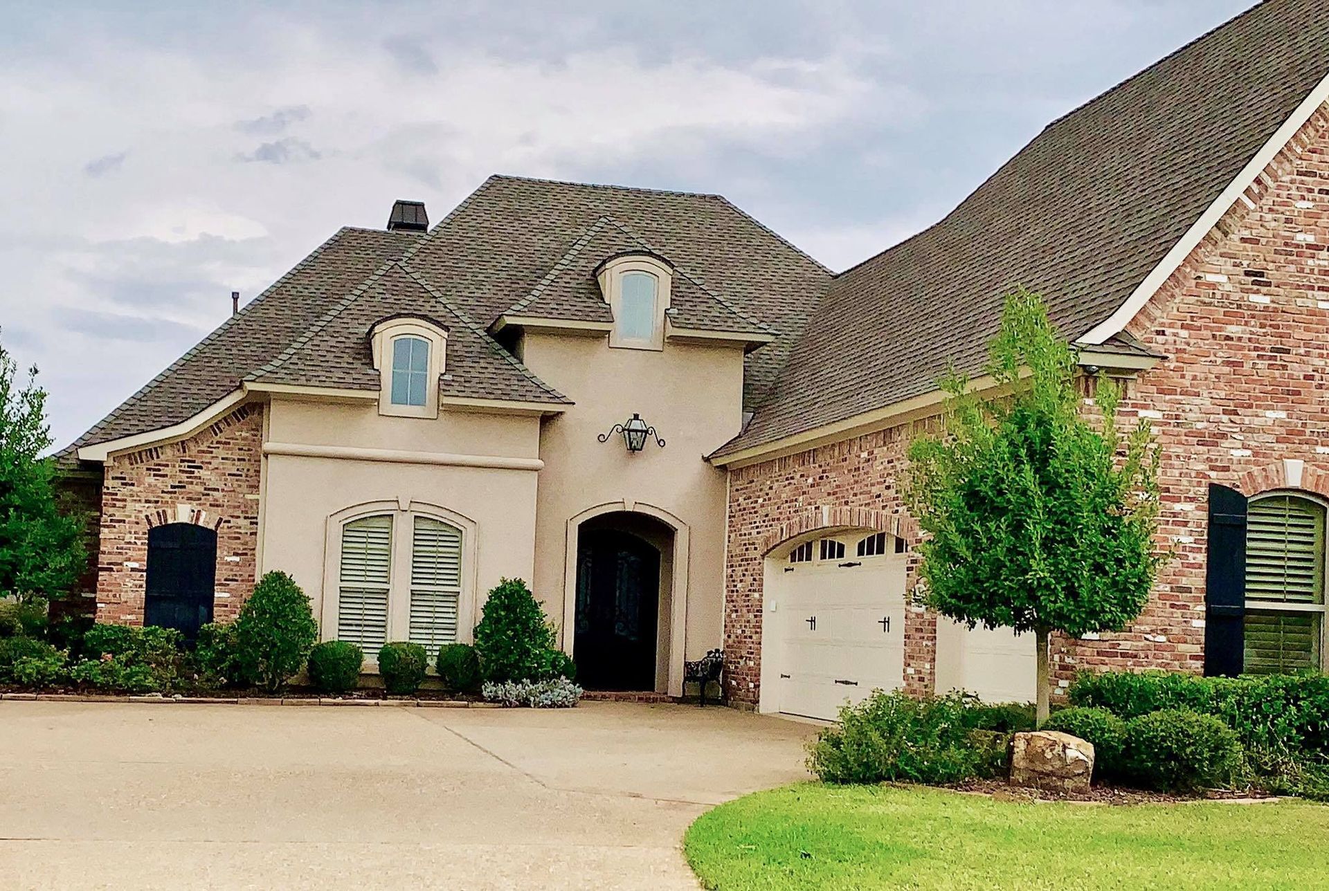 A large brick house with a large driveway in front of it