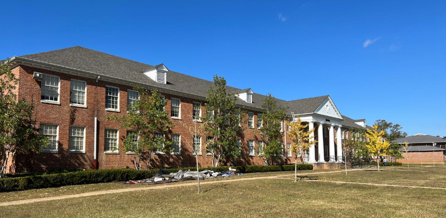 A large brick building with columns and a blue sky in the background