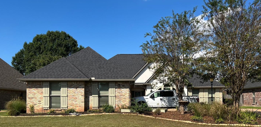 A large brick house with a black roof and a white van parked in front of it.