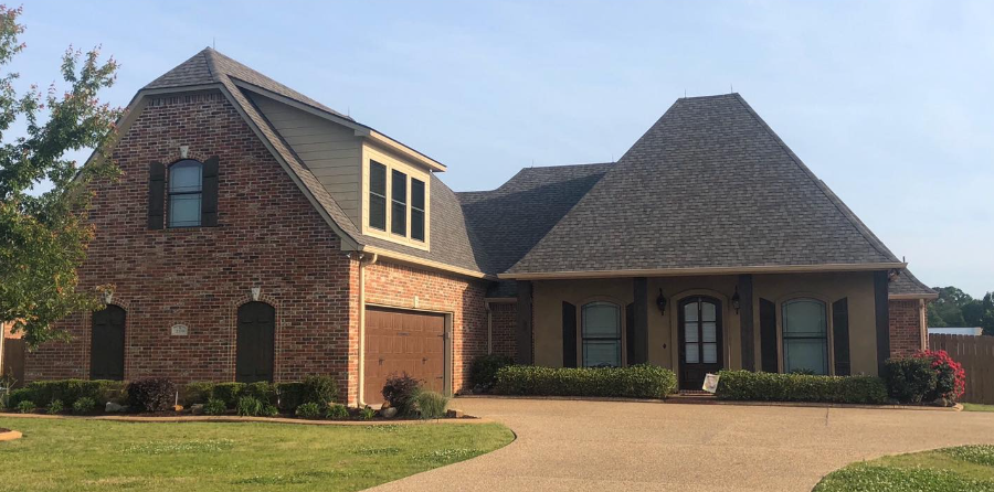 A large brick house with a garage and a driveway in front of it.