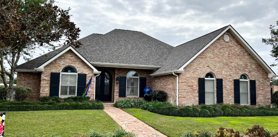 A large brick house with a gray roof and black shutters.