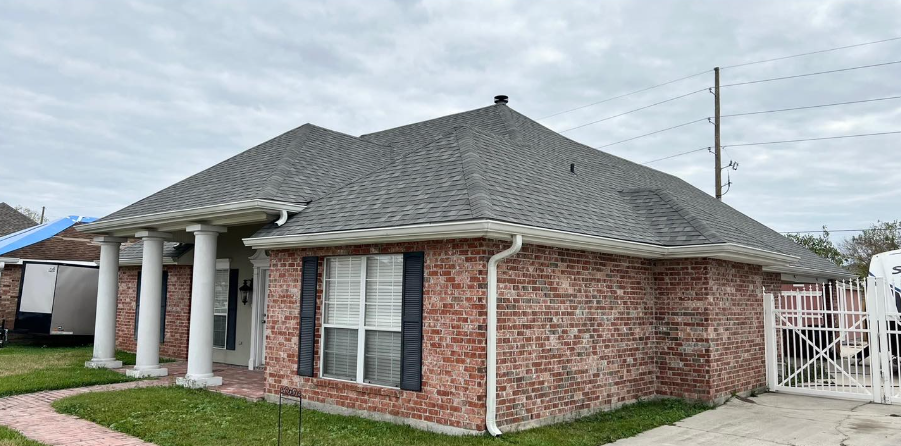 A brick house with a gray roof and black shutters.