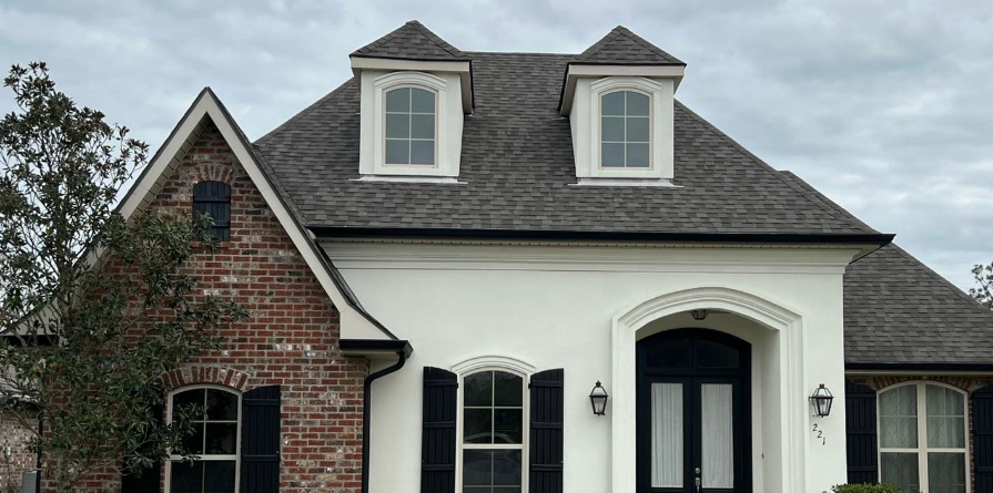 A white brick house with black shutters and a gray roof.