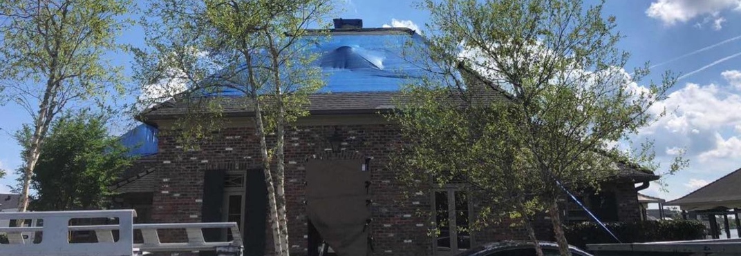 A house with a blue tarp on the roof.