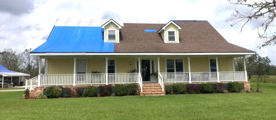 A house with a blue roof is sitting on top of a lush green field.