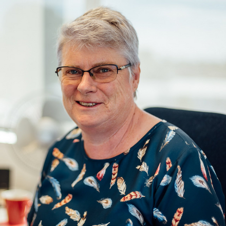 A woman wearing glasses and a blue shirt with feathers on it