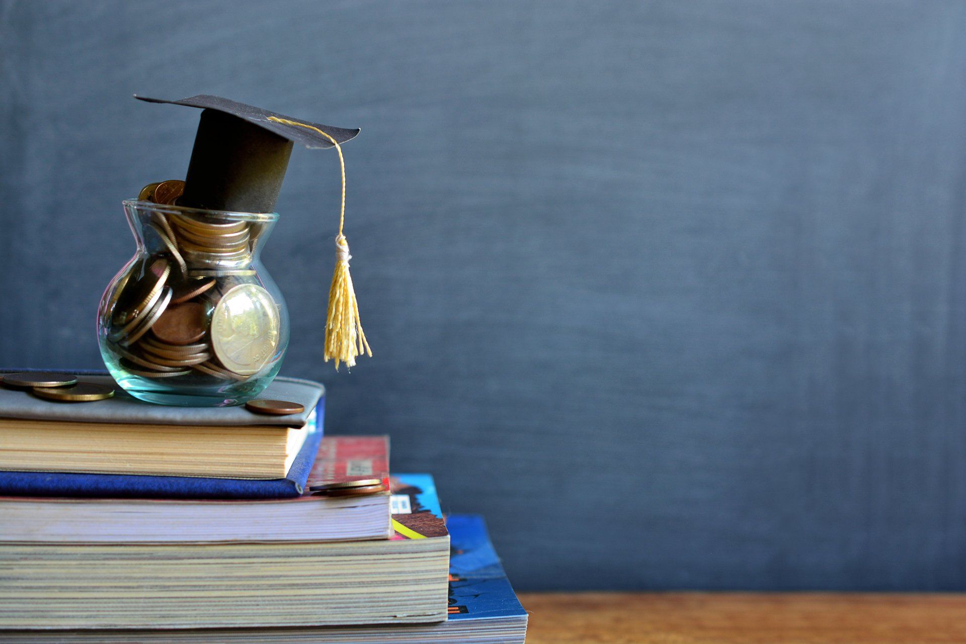A graduation cap is sitting on top of a stack of books.