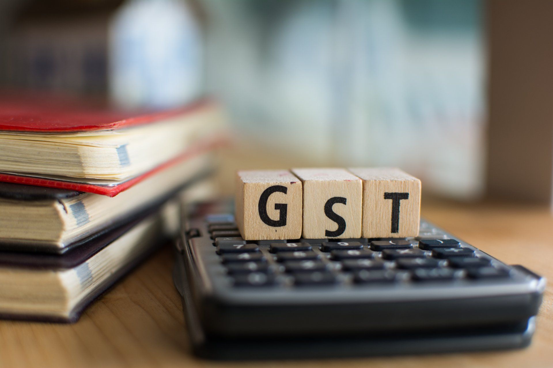 The word gst is written on wooden blocks sitting on top of a calculator.