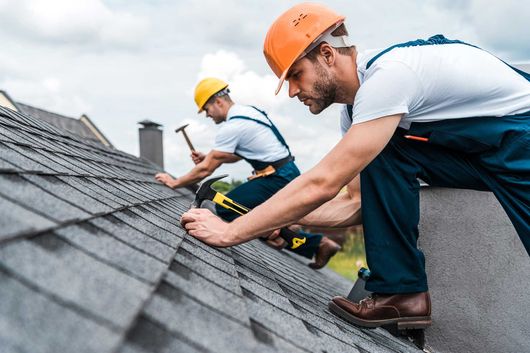 selective focus of handsome handyman repairing roof with coworker 
