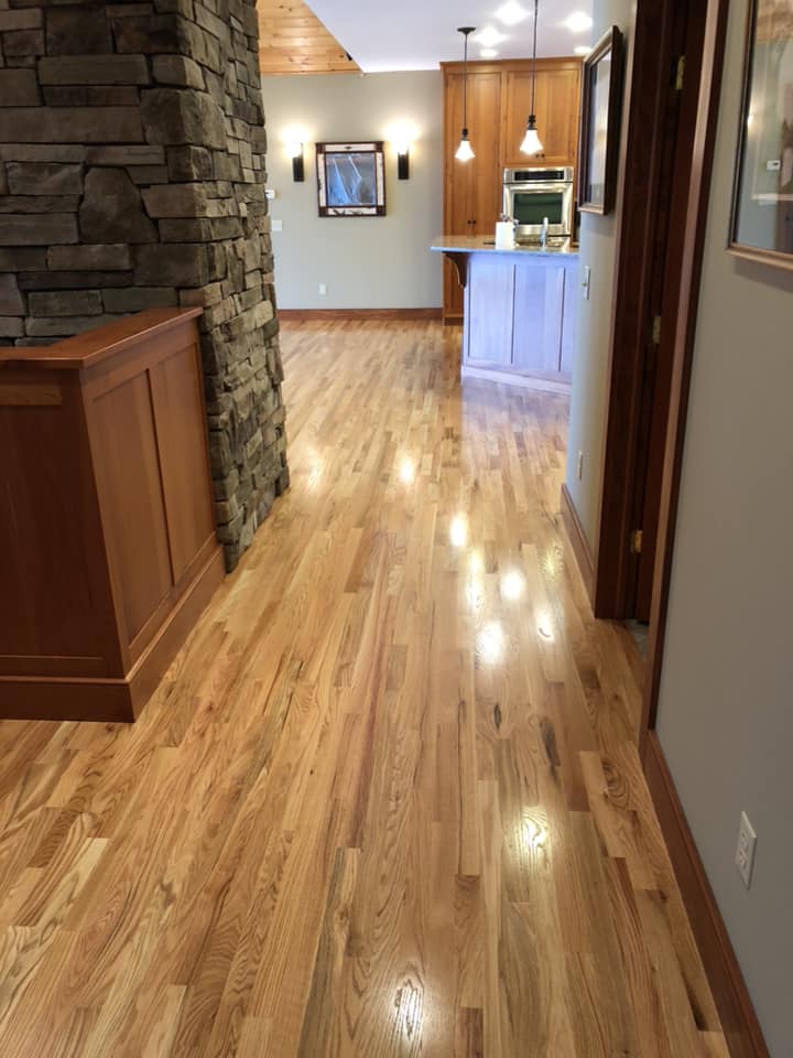 A hallway with hardwood floors leading to a kitchen