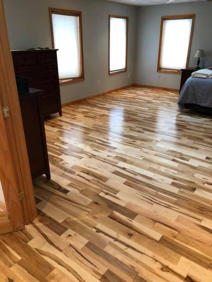 A bedroom with hardwood floors and a bed.