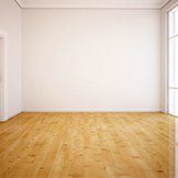 An empty room with a wooden floor and white walls.
