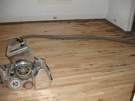 A machine is sanding a wooden floor in a room.