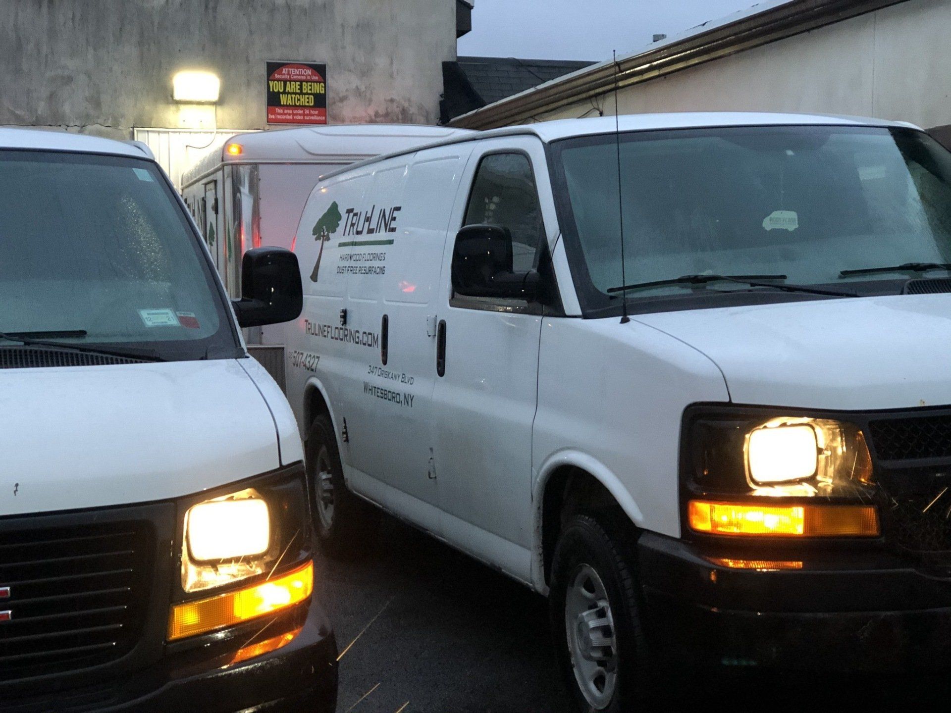 Two white vans are parked next to each other and one has the word reve on the side