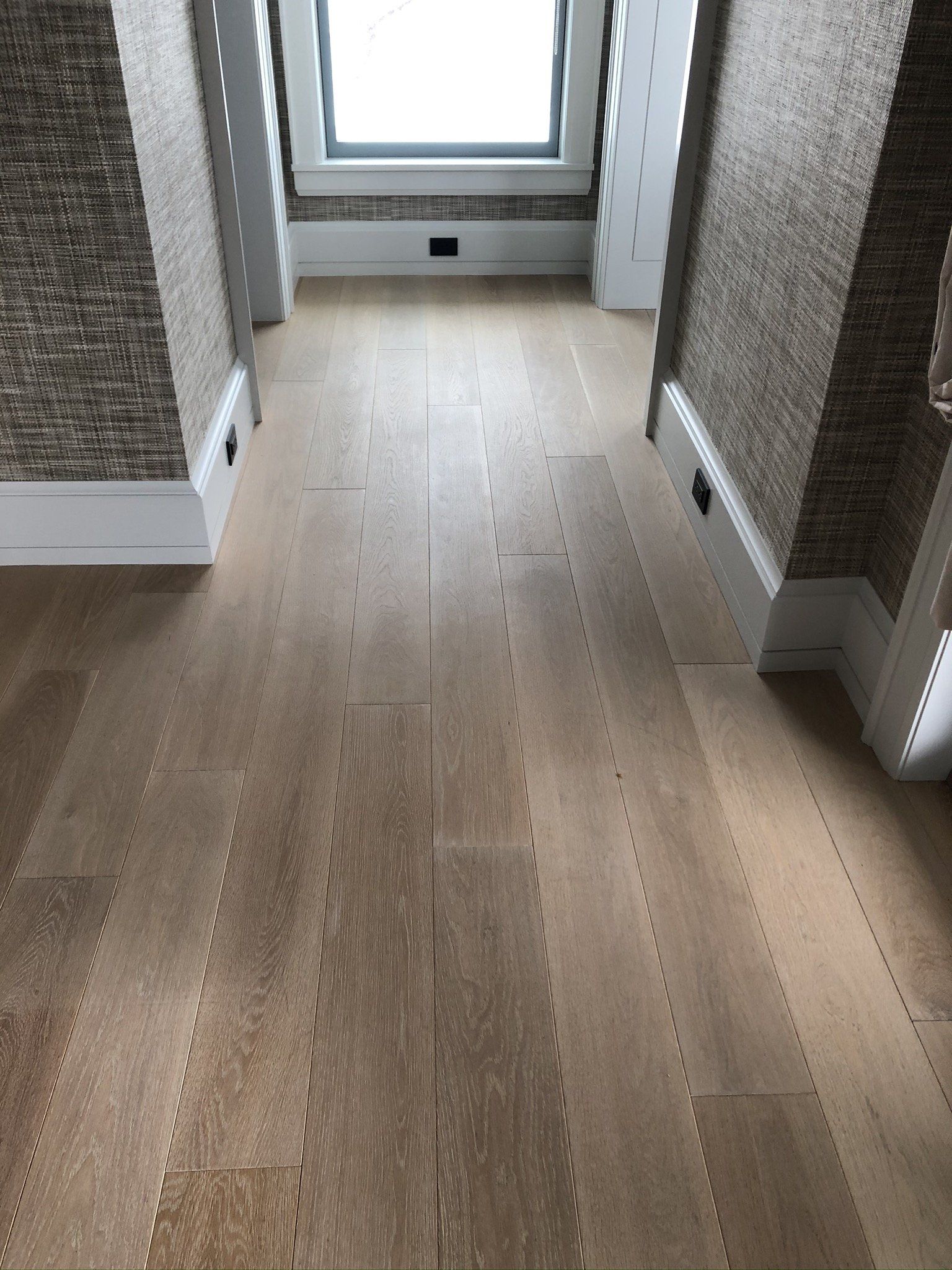 A hallway with a wooden floor and a window