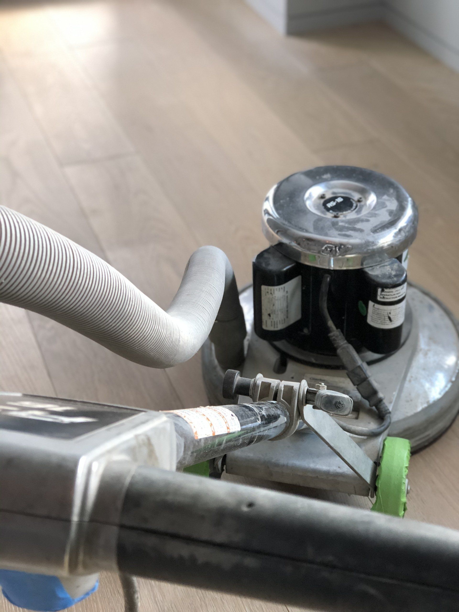 A person is using a machine to clean a wooden floor.