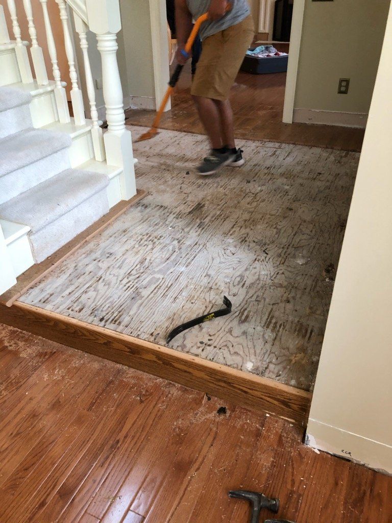 A man is cleaning the floor of a house with a broom.