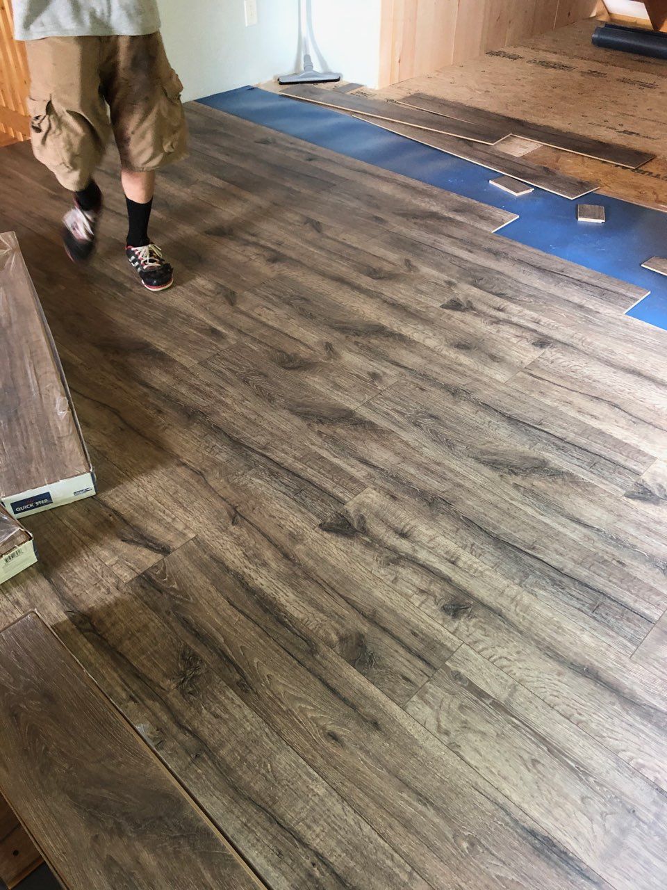 A man is walking on a wooden floor in a room.