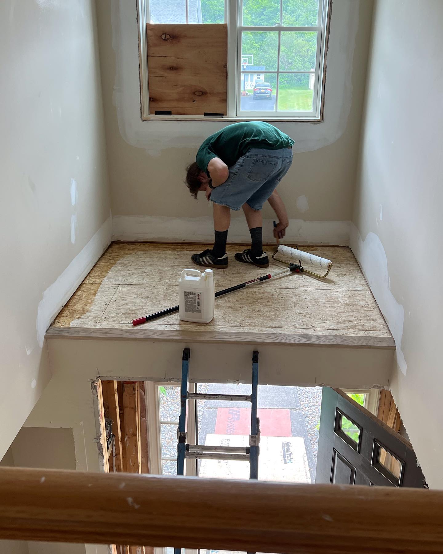 A man is kneeling on a wooden floor in a room with a ladder.