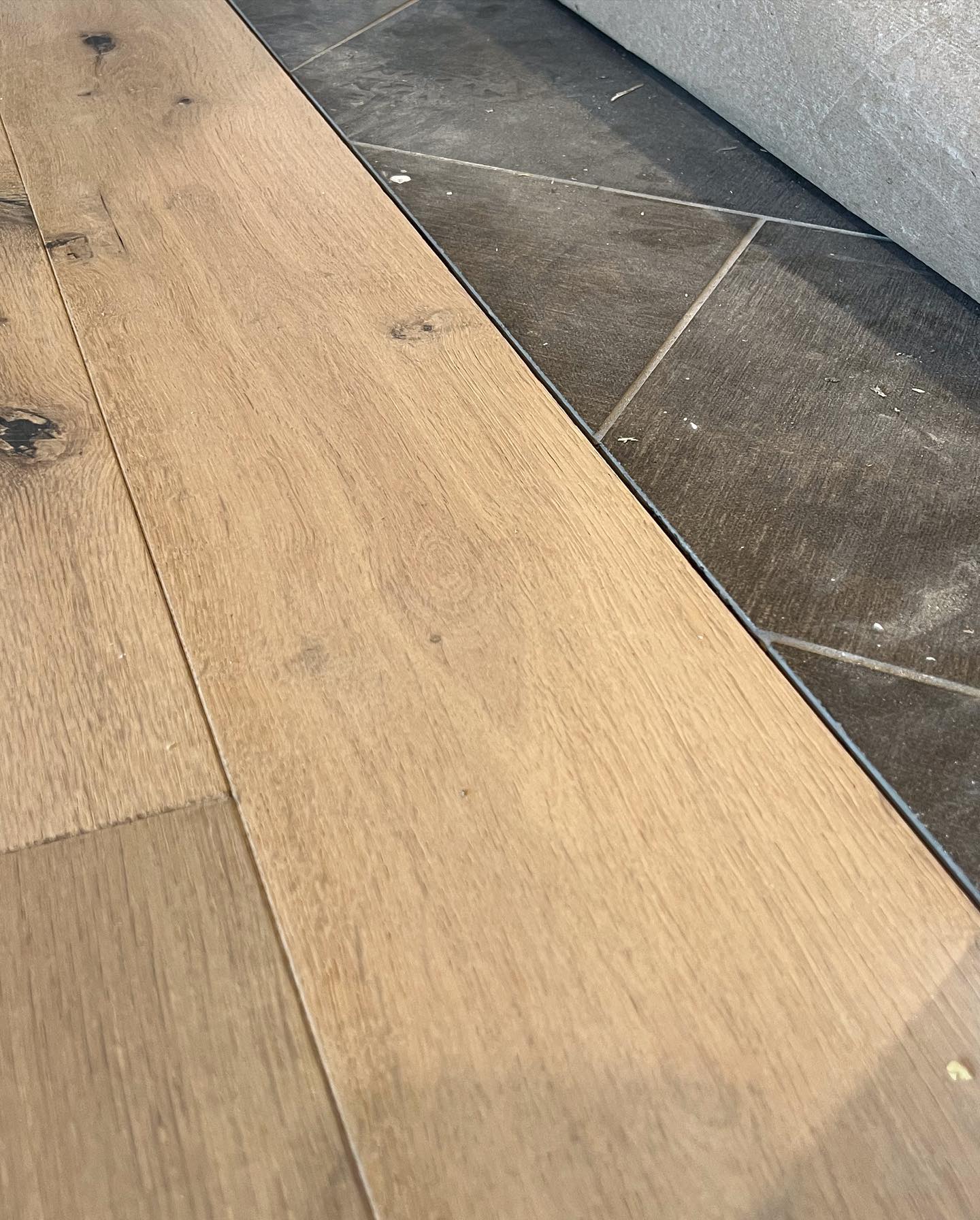 A close up of a wooden floor next to a tiled floor.