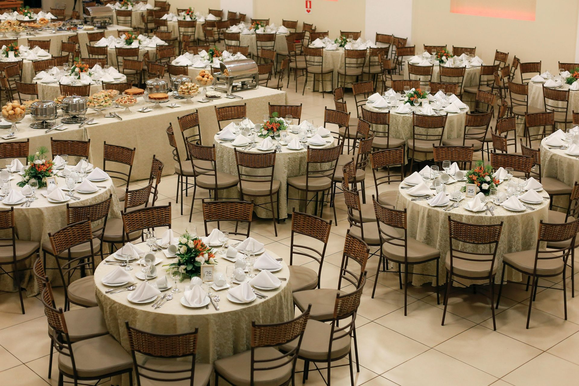 Banquet hall with round tables set for a formal event, decorated with white linens and floral centerpieces