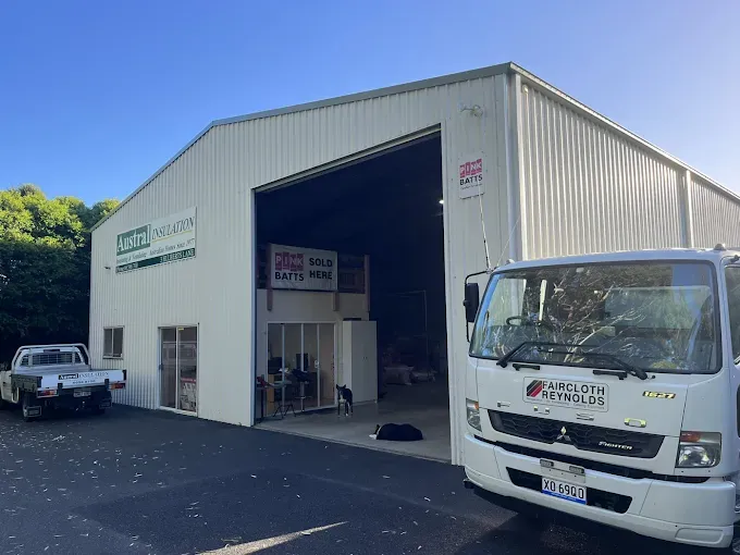 White warehouse with open bay door; a truck and pickup truck parked in front — Austral Insulation In Toormina, NSW