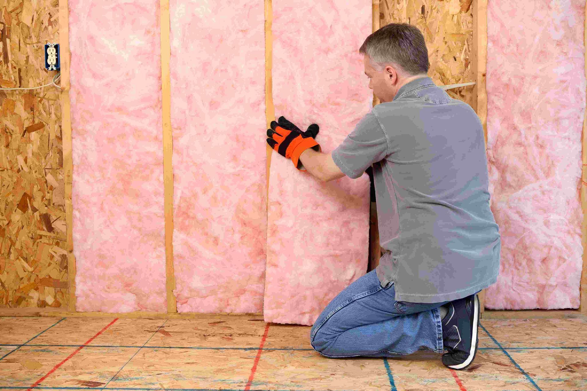 A Man Is Kneeling Down Installing Insulation — Austral Insulation In Toormina, NSW